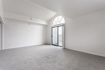 A room with a carpeted floor and a large arched window.